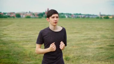 Genç adam koşuyor, kaslarını ısıtıyor, dayanıklılık ve nefes alma egzersizleri yapıyor. Genç erkek ısınmak ve dayanıklılığı ve nefes kontrolünü arttırmak için koşuyor. Çocuk koşuyor.