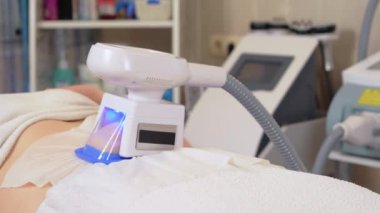Genç, geniş kadın müşteri, kozmetoloji kliniğinde karnı üzerinde kriyolipoliz prosedürü uygulanıyor. Deri altı yağ ve doğru şekli etkilemenin modern metodu