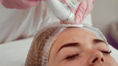 Güzellik uzmanı kadın estetik merkezinde su maskesi kullanıyor. Hasta yüz bakımı alıyor. Cilt suyu ve dokusunun iyileştirilmesine yardımcı olan prosedür