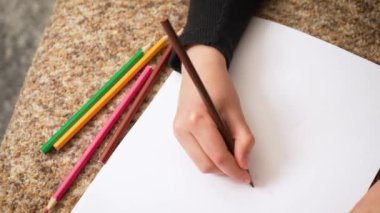 Renkli kalemlerle kız eli çizimi, çocukların yaratıcılığı. Genç bir çocuk renkli kalemlerle sanat yaratıyor. Küçük kız eli kapalı renkli kalemler kullanarak sanatsal bir ifade sergiliyor.
