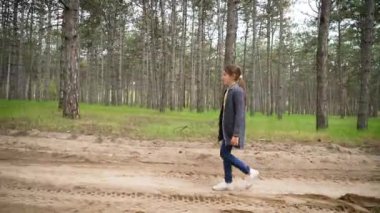 Çam ormanında yürüyen yalnız bir kız. Yalnız başına ormanda çam ağaçlarında gezinen bir kız. Huzurlu çam ormanlarında tek başına dolaşan genç kız.