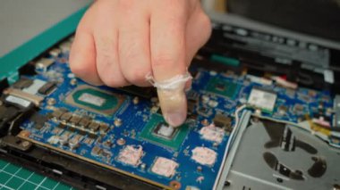 Tamirci bakım sırasında dizüstü bilgisayar GPU 'suna termal macun yayıyor. Teknisyen daha iyi ısı dağılımı için bileşik uyguluyor. Optimum sıcaklık için pürüzsüz termal yapıştırıcı kaplaması sağlama uzmanı