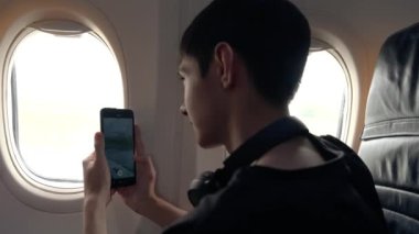 Küçük bir çocuk bir uçağın penceresinin yanında otururken cep telefonuyla havalanan uçakları yakalıyor. Manzara büyüleyici ve heyecan verici..