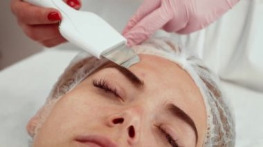 Güzellik uzmanı kozmetoloji stüdyosunda ultrasonik yüz temizleme cihazı kullanıyor. Gelişmiş teknolojiyle hassas cilt bakımı uzmanı