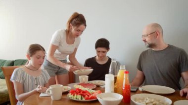 Mutlu aile, yemek vaktinin tadını çıkarmak için masanın etrafında toplandı. Annem taze kaynamış hamur köftelerini tabakta servis ediyor. Sıcak atmosfer gülümseme ve lezzetli ev yemekleri ile dolu sıcak bir aile yaratıyor.