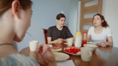 Aile, yemek masasında mutlu bir anı paylaşıyor. Anne oğul ve kız birlikte yemek yiyorlar. Ev yemeğinin tadını çıkarıyorlar. Grubun taze yemeklerinin tadını çıkarması kaliteli aile zamanı.
