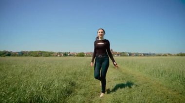 Çıplak ayakla özgürlük ve pozitifliği ifade eden mutlu bir kadın. Çıplak ayaklı kadın güneşli alanda zarif bir şekilde dans ediyor, kendine güven ve neşe saçıyor. Neşeli bayan ritim tutuyor.