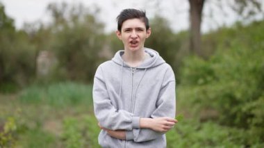 Genç çiftçi çocuk sebze bahçesinin önünde kuş yaprağı yiyor. Ergenlik çağındaki çiftçi arka planda kuş yaprağını kemiriyor. Çiftçi çocuk çiftlikte kuş yaprağı tadıyor.