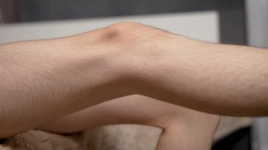 Kıllı erkek bacağını diz çökerek kapat. Detaylı atış, kıllı bacak diz çöker. Yaklaş çocuk bacağı, dizlerinde kıllar var.