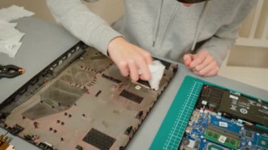 Çocuk bakım sırasında dizüstü bilgisayarın altını bezle temizliyor. Dikkatlice iç kaplamalardan toz ve enkazı temizliyorum. Hava akışını ve genel performansı artırmak için dizüstü bilgisayar bileşenleri düzenleniyor