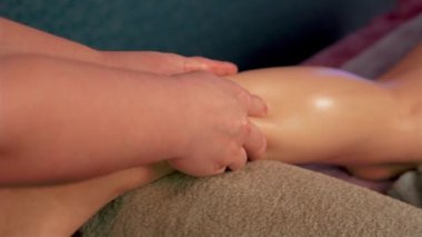 Güzellik salonundaki genç bayana masaj yapan kadın bacakları ve kalçaları. Kadın antiselülit alıyor. Derin doku buzağılarını rahatlatıyor.