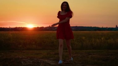 Gün batımında tarlada neşeyle dönen bir kadın neşeli enerji ve zarafet saçıyor. Alacakaranlıkta neşeli bir şekilde dönen kadın canlı bir ruh hali ve canlı bir hareket sergiliyor. Dans eden ve altın sarısı dönen kadın