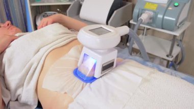 Modern kozmetoloji kliniğinde kriyolipolisis yağ tedavisi prosedürü. Belinde aşırı deri altı yağ olan tombul bir kadın kozmetoloji salonunda kriyolipoliz tedavisi uyguluyor.