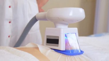 Güzellik uzmanı, kozmetoloji kliniğinde özel aleti olan geniş bir kadına kriyolipolisis prosedürü uyguluyor. Güzellik kliniğinde vücut bakımı prosedürü. Kriyoterapi. Şişman aşırı tedavi