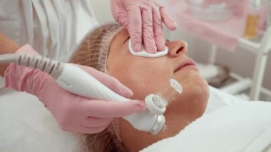 Güzellik uzmanı kadın spa salonunda hidrakiyal ekipman kullanıyor. Hasta yüz tazeleme tedavisi görüyor. Tedavi, cildin sulanmasına ve temizlenmesine yardımcı olur.