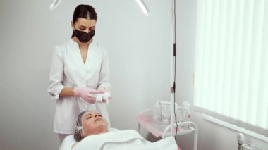 Cilt bakımı uzmanı cilt bakımı için hazırlanıyor. Profesyonel temizlik ve hijyeni sağlarken aynı zamanda müşteri ihtiyaçlarına odaklanıyor. Deri sağlığını destekleyen bir terapist.