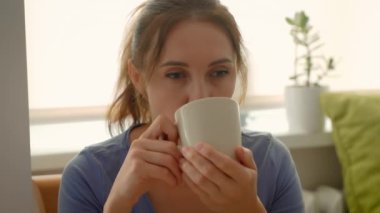 Kahve ya da çay içen bir kadın. Kadın sakin bir ifadeyle rahatlatıcı içecekten hoşlanıyor. Rahatlatıcı içkinin kıymetini bilen bayan.