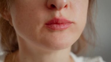 Tanınmayan bir kadın hamur tatlısı yiyor ve çiğniyor. Dişi, yiyeceğin tadını dudaklarına yakın çekim odaklanarak çıkarıyor. Yemeğin tadını çıkaran kadın detaylı ve samimi yemek anında.