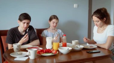 Aile yemeğinde çocuklarla yemek yiyen bir kadın. Yemek sırasında çocuklarla yemek yiyen bir kadın. Bayan, evde yemek yerken oğlu ve kızıyla eğleniyor.