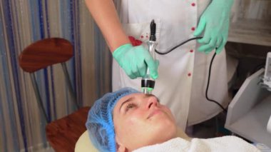 Güzellik kliniğinde donanım ultrason kozmetik prosedürü. Cilt tazeleme, anti-yaş terapisi. Güzellik uzmanının elleri kadın hastalarla çalışıyor.