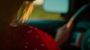 Yumuşak akşam güneşiyle çevrili arabayı süren kadın sıcak bir parıltı yaratıyor. Sakin günbatımı yolculuğu sırasında kadın bir direksiyon simidi. Altın ışık sükuneti artırırken, bayan yön bulma yolu