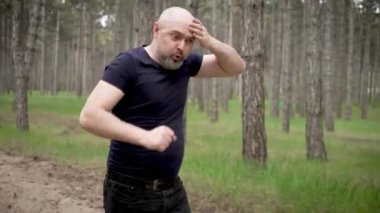 Ormanda koşuşturan komik bir komedyen. Komik erkek ağaçların arasında şakacı bir şekilde koşuyor, aptalca davranıyor. Komik adam ormanlık alanda koşuşturuyor, şakalaşıyor ve eğleniyor.
