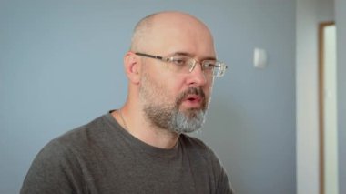 Kel, aç bir adam çatalla hamur köftesi yiyor. Kel erkek hamur tatlısı tutarken yemeğin tadını çıkarıyor. Kel adam, gevşemiş yemek saatinde yemeğin tadını çıkarıyor.