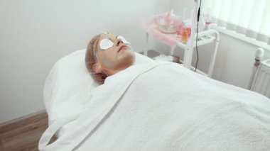 Müşteri ileri estetik stüdyosunda yüz maskelerini yenilemekten zevk alıyor. Deri canlılığını arttırmak için tasarlanmış besleyici tedavi altında dinlenen bir kadın. Rahatlamak için pamuk pedleri kullanıldı