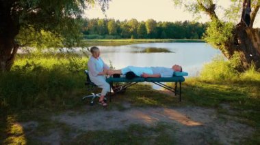 Ağaçların altında doğaya masaj yapmak. Deri masajı yaptıran bir adam, vücut akapunktur. Masaj spa tedavisi konsepti. Doğada yeşil ağaçların altında profesyonel masaj