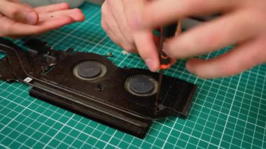 Baba oğul dizüstü bilgisayar soğutma sistemini tamir ediyor, tornavida tutuyor ve vantilatörler üzerinde çalışıyor. Isıtıcıyı tamir eden, vidaları hassasiyetle ayarlayan çocuklu bir erkek. Çocuklu bir adam donanımı parçalıyor.