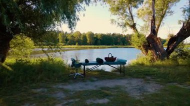 Nehir kenarındaki masaj masası terapi için sakin bir ortamda yemyeşil doğayla çevrili. Rahatlama ve sakinleştirme prosedürü için açık hava düzenlemesi hazır. Huzurlu nehir kenarı masaja hazır.