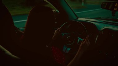 Akşamları araba süren bir kadın, elinde direksiyon, yumuşak ışık altında sakin bir iç mekan. Kadın direksiyon aracı, navigasyon yolu, pencerelerden görülebilen huzurlu kırsal bölge. Tutan kadın