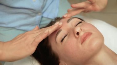 Terapist, rahatlamak ve dengeyi sağlamak için alnına nazikçe masaj yapıyor. Sakinleştirici ve gençleştirici etkileri arttırmaya çalışıyorum. Ruhsal refahı arttırmak için profesyonel canlandırıcı alın. Uzman