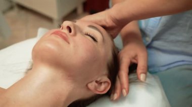 Yaşlanma karşıtı yüz masajı, terapi sırasında masöz elleri. Kaplıcada yüz masajı yaptıran bir kadın. Spa, sağlık, kafa masajı, yüz ve cilt bakımı