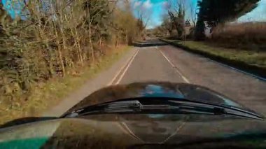 Leicester, Leicestershire, Birleşik Krallık, Avrupa, sol el trafiği boyunca giden ilk kişi SUV 'yi görüyor. POV Yolu macerası parlak mavi gökyüzü altında, sakin