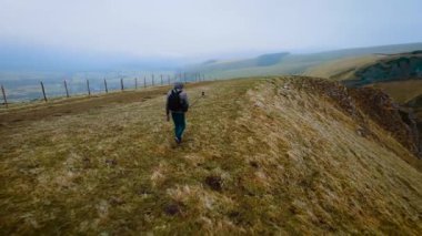 Selfie kameralı blogcu adam dağlarda seyahat videosu çekiyor. Yürüyüşçü, İngiltere 'nin Peak District bölgesinin engebeli arazisinde içerik oluşturuyor. Manzarayı ve sisli manzarayı keşfeden erkek.