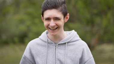 Neşeli, neşeli, yanaklarını havayla şişiren ve parmaklarıyla üfleyen genç çocuk. Neşeli ergenler oynaşıyor. Mutlu genç adam aptalca davranıyor, yanakları havayla dolduruyor ve üflüyor.