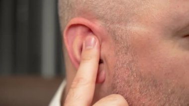 Kulağı parmaklarıyla karıştıran adam. Kıllı kulağı parmaklarıyla kazan bir erkek. Parmağıyla kulağını kaşıyan adam.