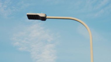 Mavi gökyüzüne karşı kavisli direği olan modern sokak lambası. Enerji verimliliği için tasarlanmış kentsel aydınlatma armatürü. Gösterişli lamba direği. Yayalar için aydınlatma sağlayan halka açık yol lambası ve