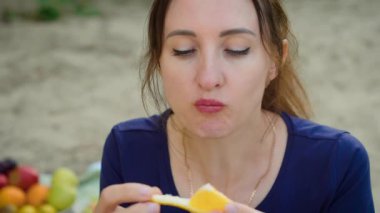 Düşünceli bir ifadeyle turuncu yiyen ve sakin odaklanan bir kadın. Yansıtıcı bir ruh hali içindeyken portakal dilimini tutan kadın. Bayan narenciye tadı alıyor, sakin ve sakin bir tavırla.