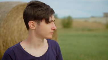 Kırsal alanda patates cipsi yiyen bir çocuk. Açık arazide çıtır çıtır cipslerle atıştıran bir genç. Genç erkek, doğal kırsal atmosferde tuzlu cipslerin tadını çıkarıyor.