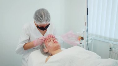 Kadın doğal güzellik tedavisi uyguluyor. Deri dokusunu ve berraklığını arttırıyor. Moda odaklı bir kadın cilt bakımı rutini. Yenilenme işlemi gören kız, pürüzsüz ve