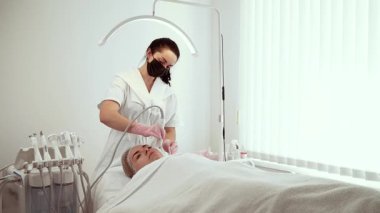 Kozmetik dermatoloji kliniğinde vakum yüz temizleyici kullanan kozmetik uzmanı. Kadın uzmanlar derin arınma ve gözeneklerden arındırma yapıyor. Bayan Güzellik Uzmanı