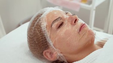 Susuzluk tedavisi sırasında dinlenen bir kadın. Hasta bütünsel güzellik merkezinde gençleştirici bakım görüyor. Şeffaf paket cilt ürünlerinin emilimini artırır