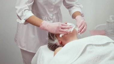 Cilt bakımı uzmanı yüzünü nazikçe temizliyor, hasta rahatlıyor. Bakım için yumuşak teknikler kullanan bir sağlık merkezi çalışanı. Güzellik uzmanı parlayan cilt için kapsamlı bir tedavi sağlıyor.