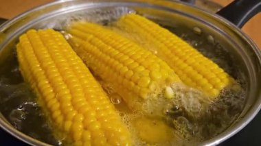 Pişirme işlemi sırasında haşlanmış mısır ve kaynayan su. Sağlıklı hazırlanmak için sıcak buharda pişmiş tatlı sarı mısır. Fırında taze mısır pişiriyorum. Paslanmaz tencerede, vitrinlerde.