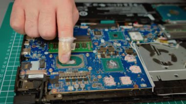 Laptop işlemci yüzeyine eşit olarak termal yapıştırıcı yayılıyor. Uygun ısı dağılımı için CPU 'nun düzgün bir şekilde korunmasını sağlıyorum. Geliştirilmiş soğutma işlemi sırasında bileşiği dikkatlice uygula
