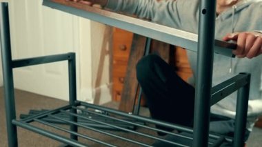 Adam istikrar için ahşap rafları monte ediyor. Erkek mobilya çerçevesini uygun hizaya getiriyor. Güvenilir bir depo sağlama alıyor. Sağlam için işçi yerleştirme bileşenleri