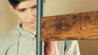 Askıdaki tahtayı tutturmak için elektrikli matkap kullanan bir adam. Güçlü ve dayanıklı mobilyalar için metal çerçeve oluşturan bir erkek. Güvenilir bir depo için güvenli eklenti sağlayan bir adam. İşçi hizalaması