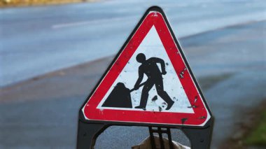 Birleşik Krallık 'ta yol çalışması uyarısı. Trafik danışma kurulu ileride İngiltere 'de inşaat olduğunu belirtiyor. Yol tehlikesi işareti İngiltere 'de bakım altındaki alanı gösteriyor